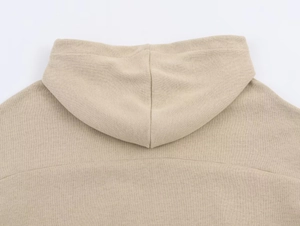 Detail view of the soft knitted texture and stitching on the beige hooded sweatshirt