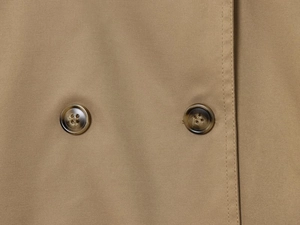 Detailed close-up of khaki trench coat twill fabric and brown tortoiseshell buttons