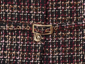 Close-up of multicolor tweed texture with gold metal buckle and black belt details