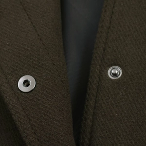 Close-up of metallic snap button on heavy brown wool jacket with sleek black lining