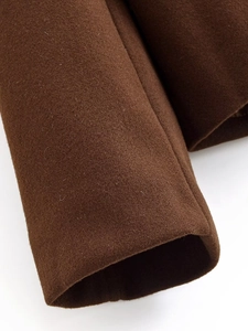 Dettaglio macro del polsino di un cappotto di lana marrone scuro con trama pregiata