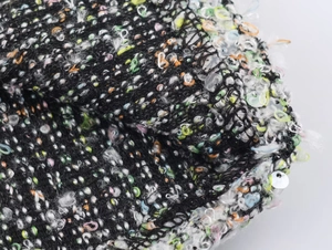 Détail macro de paillettes multicolores sur tissu tweed noir pour ensemble femme