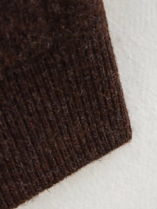 Détail du tissu en maille côtelée marron foncé montrant une texture pelucheuse et un tissage