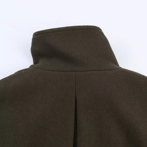 Macro detail of dark olive wool jacket featuring textured twill fabric and stand-up collar