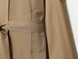 Detail of khaki trench coat waist belt featuring durable twill fabric and premium double stitching