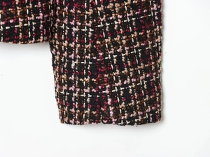 Close-up of multicolor tweed jacket cuff showing premium black and burgundy textured weave