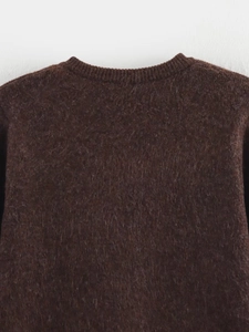Gros plan sur le pull en maille marron foncé montrant le col rond et la texture douce en mohair