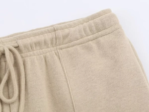 Detailed macro view of beige knit pants featuring elastic waistband and woven drawstring ties