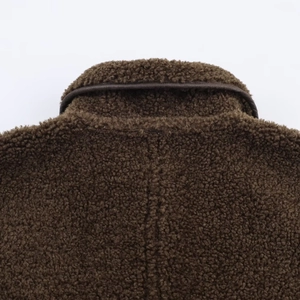Detail of dark brown reversible sherpa jacket featuring leather piping and stitching