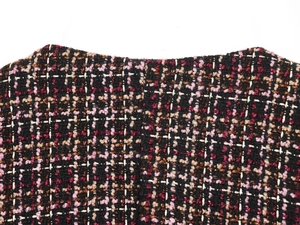 Macro shot of multi-color tweed fabric showing black, pink, and burgundy woven textures