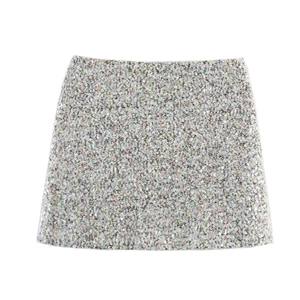 Gros plan détaillé sur la texture du tissu à paillettes colorées du short trapèze pour femme