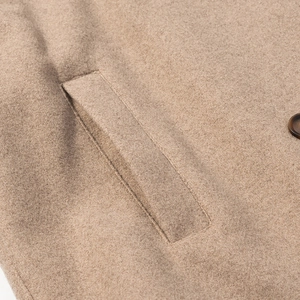Detailed close-up of a camel wool coat featuring side pocket and textured fabric finish