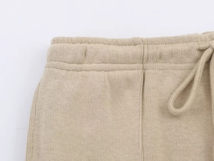 Close-up of the elastic waistband with adjustable drawstring on khaki knit trousers