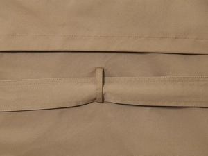 Detail of khaki trench coat showing waist belt loops and high-density cotton twill fabric