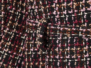 Macro shot of colorful tweed fabric texture and woven belt loop on the autumn jacket