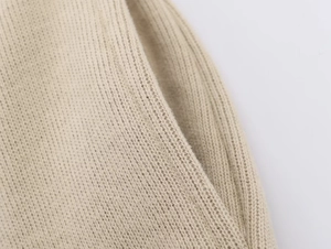 Close-up of beige knitted hoodie fabric showing fine stitching and pocket detail