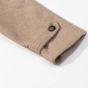 Macro detail of camel wool coat sleeve with buttoned strap and neat stitching