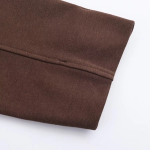 Détail macro du tissu tricoté marron foncé avec couture précise sur le bord du blouson