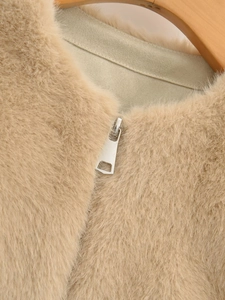 Close-up of fluffy faux fur vest featuring a silver metal zipper and soft suede lining