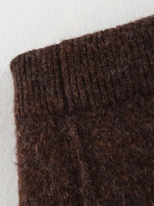 Gros plan sur les poignets côtelés et la texture laineuse de la tenue en tricot