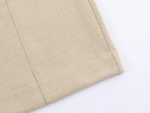 Close-up of beige knitted hoodie hem showing high-quality stitching and fabric texture