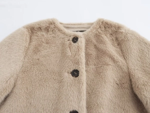 Détail de la veste courte en fausse fourrure beige avec col rond et boutons marron
