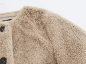 Détail d'une veste en fausse fourrure marron clair avec texture douce et boutons en résine