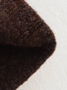 Gros plan détaillé sur la texture tricotée marron foncé avec des fibres douces en peluche