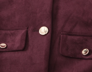 Detailed macro view of burgundy suede blazer with golden metal buttons and flap pockets
