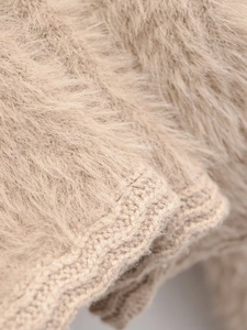 Macro shot of fluffy beige faux mink fur cardigan showing soft knit texture and ribbed cuff