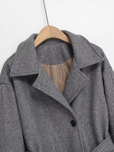 Détail du col d'un manteau en laine gris avec de larges revers et un bouton noir