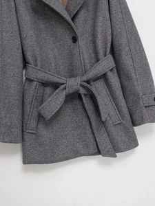 Détail de la texture d'un manteau gris avec col à revers et boutons noirs à simple boutonnage