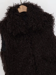 Detail of dark brown faux fur vest with dense plush texture on a wooden hanger