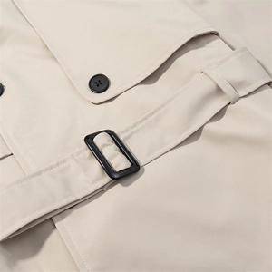Detail of beige trench coat featuring adjustable waist belt with black buckle and fine stitching