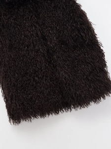 Close-up of premium black faux fur texture with long fluffy fibers on a winter vest