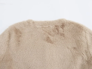 Détail du col rond et de la texture en fausse fourrure douce d'un manteau beige