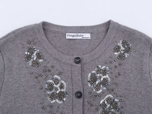 Detail of grey knit cardigan neckline showing delicate beadwork and floral sequins