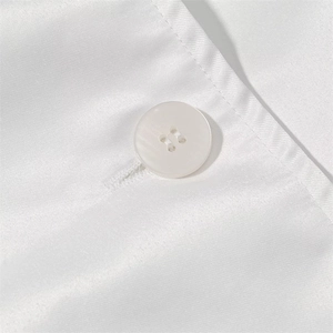 Detail shot of white four-hole button and stitching on double-breasted trench coat fabric