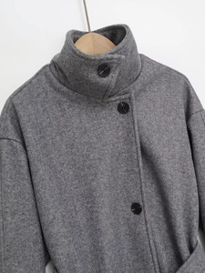 Détail d'un manteau en laine gris montrant le col, les boutons noirs et la texture