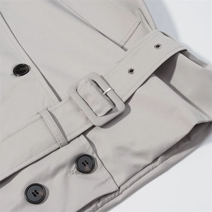 Detailed view of women's trench coat waist belt with buckle and textured buttons