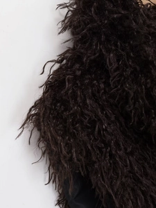Close-up of deep brown curly faux fur texture on a women's winter waistcoat vest