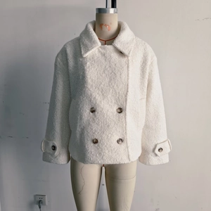 Detail of white faux wool coat featuring double-breasted buttons and lapel collar texture