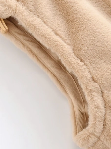 Détail macro d'un gilet en fausse fourrure camel montrant la texture douce