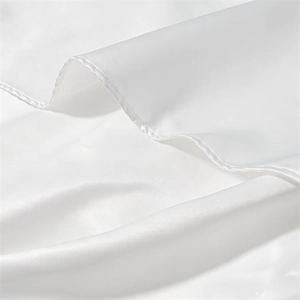 Detail of premium white satin fabric showing fine stitching and silky glossy texture