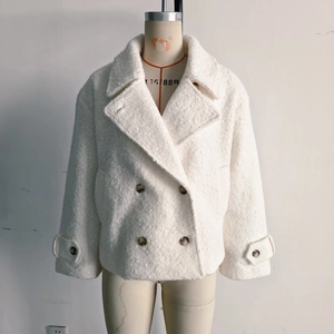 Detail of off-white boucle texture coat with notched lapels and double-breasted buttons