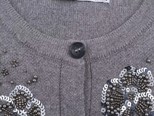 Detail of grey knit cardigan neckline showing intricate silver sequins and bead floral embroidery