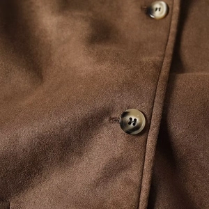 Detailed macro view of dark brown suede fabric texture and amber tortoiseshell buttons