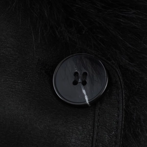 Close-up of fluffy faux fur collar and premium leather button detail on black long coat