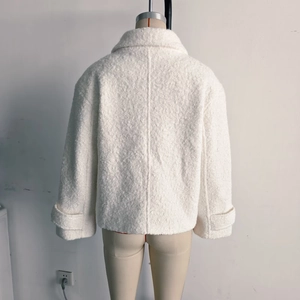 Detail view of the back of a white faux wool jacket with oversized collar and buckled cuffs