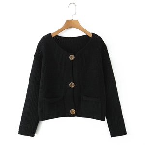 Dettaglio del cardigan nero in maglia a nido d'ape con grandi bottoni dorati e tasche